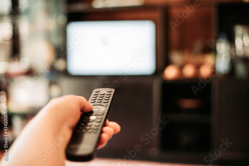 Elderly woman hand holding a remote control, changing channels