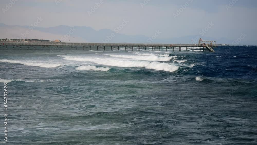 Storm on the Red Sea and pier on the background of Sinai coast. Touristic resort Sharm El Sheikh Egypt. Storm on the Red Sea and pier on the background of Sinai coast. Touristic resort Sharm El Sheikh Egypt.