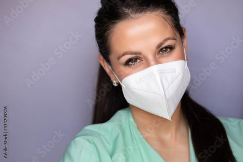 Young medical professional with mask and smiling eyes. Isolated on gray