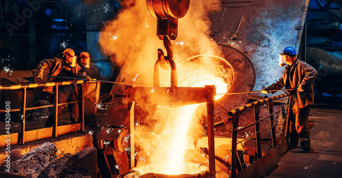 Cast iron process, liquid molten metal pouring in ladle, industrial metallurgical foundry factory, heavy industry. photo