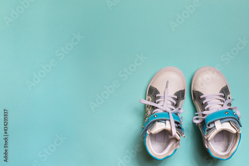 Baby girl sport shoes on blue background. Kid small size sneakers, canvas booties closeup view. Space, card invitation template.