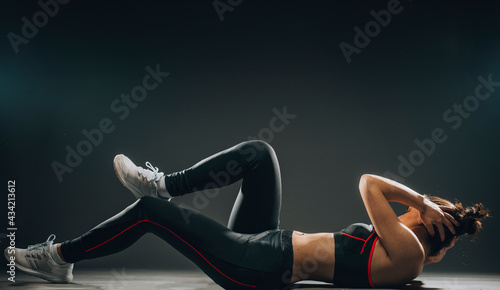 The muscular young woman athlete stretching on gray background.