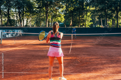 View from the back of a young female paying tennis on a court outside