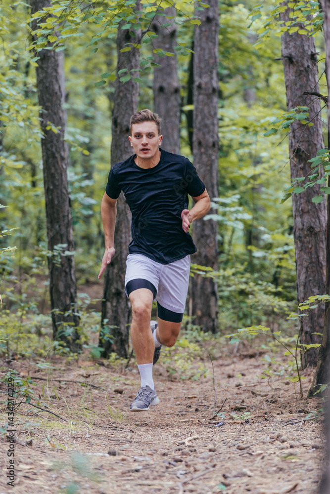 Full-length picture of an attractive male athlete running in the woods