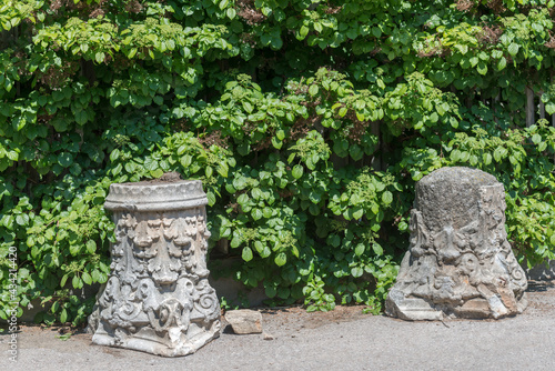 two weathered composite order capital - removed after the demolition of an old building - and now sitting unused in a garden park 
