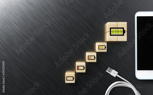 cubes with charging symbols and a smartphone and a cable on aluminum background