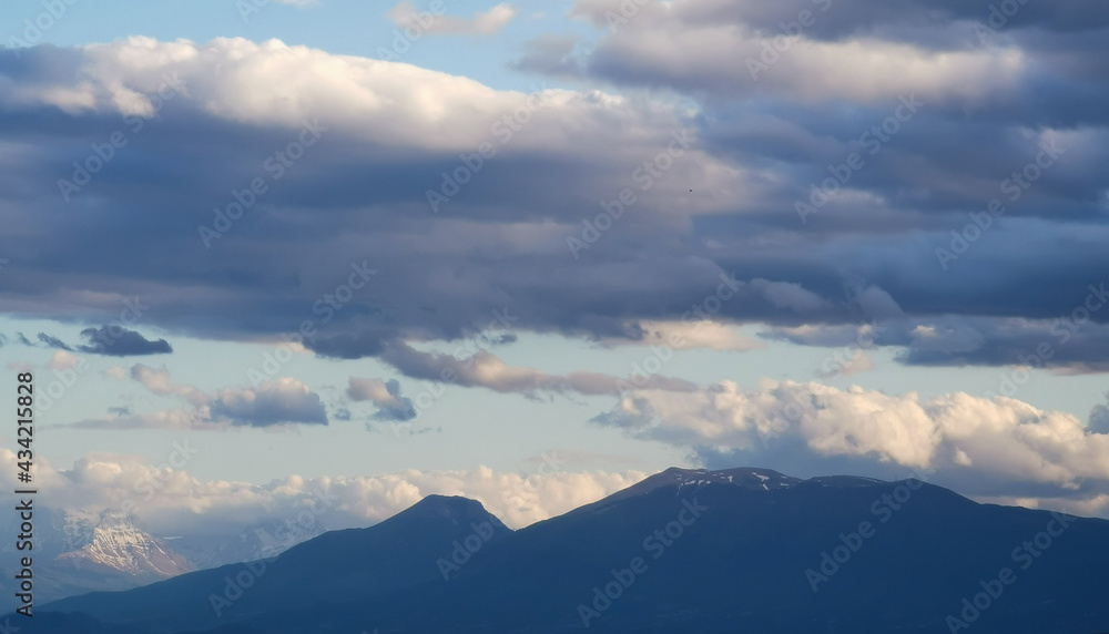 Grandi nuvole sopra le montagne dell’Appennino all’imbrunire in un cielo azzurro primaverile