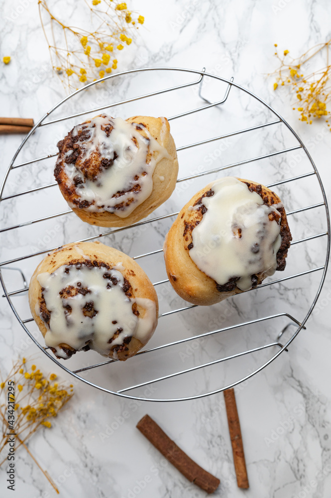 Cinnamon rolls with icing on a rack and marble background Cinnamon rolls with icing on a rack and marble background