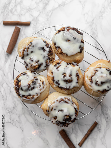 Cinnamon rolls with frosting on a rack and marble background