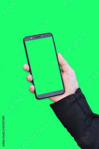 Business hand holding smartphone with green screen isolated on green background.