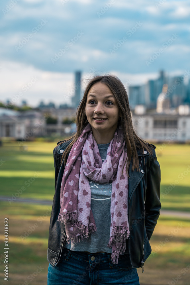 Fototapeta premium Portrait of a beautiful young woman outdoors in the city. Urban landscape. Travel and freelance lifestyle. Youth and beauty