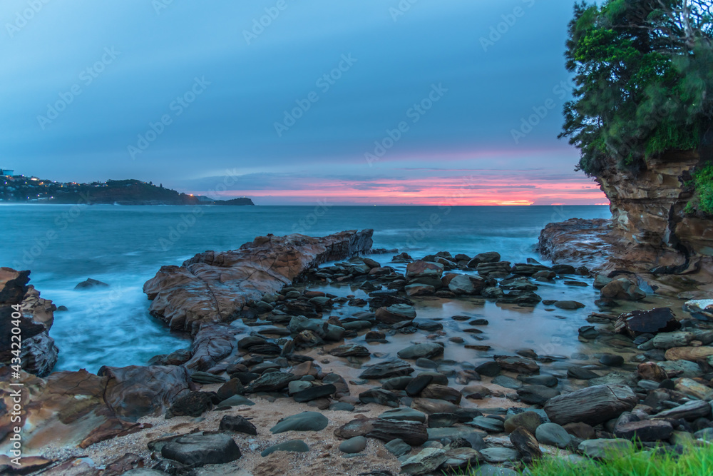 Rocky Sunrise at the seaside with cloud cover and headland