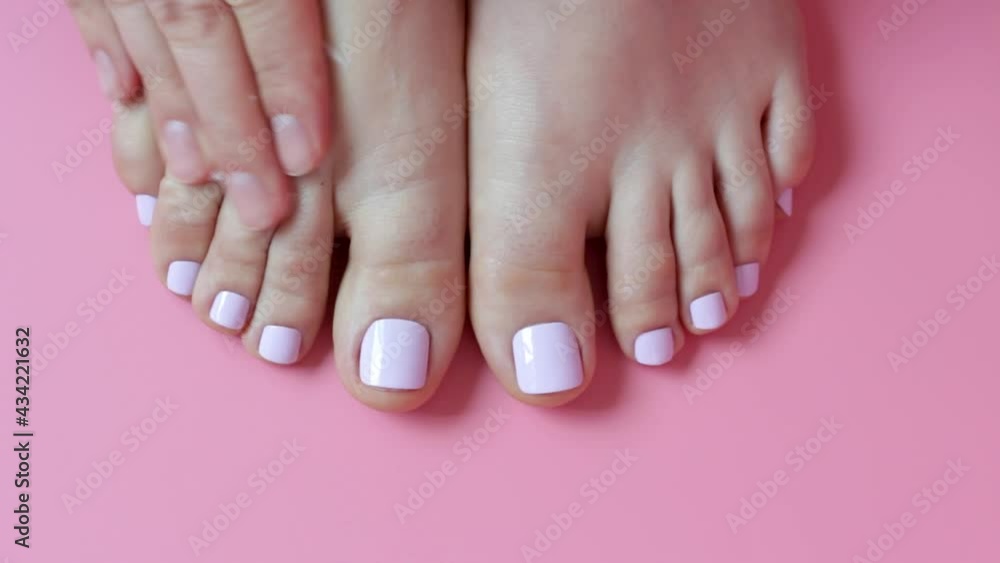 Girl smears cream on her legs with white pedicure. Girl smears cream on her legs with white pedicure.