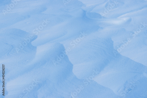 Beautiful winter background with snowy ground. Natural snow texture. Wind sculpted patterns on snow surface.