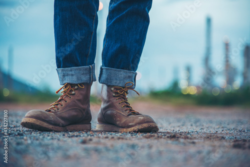 Men wear construction Boots safety footwear for worker at construction site. Engineer Wear Jeans Brown Boots Worker on Background of Refinery. Engineer safety industry fashion footwear walking outdoor
