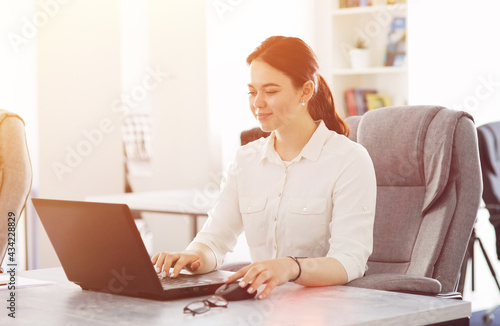 Young attractive business woman working in office smiling looking into laptop