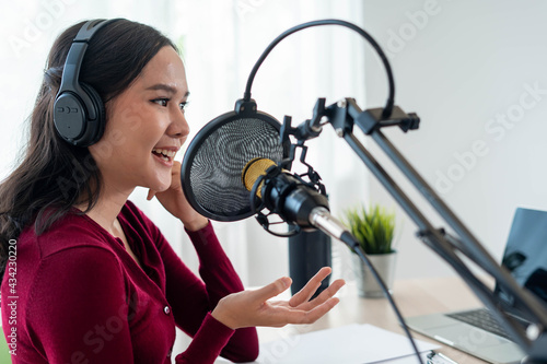 Bright Asian women record a podcast with a microphone and computer camera. A young woman work from home studio. broadcast studio concept