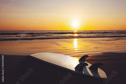 Fototapeta Naklejka Na Ścianę i Meble -  Surfboard on beach at sunset. Seascape of summer beach with sea and blue sky background.