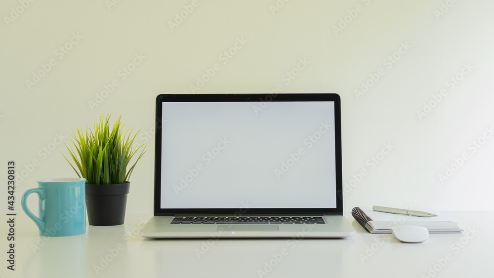 A laptop and a grass coffee mug with a notebook on the desk A laptop and a grass coffee mug with a notebook on the desk