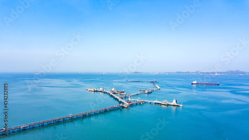 Aerial view from drone, Oil pipes to oil tanker ships at pier off the coast in beautiful peaceful environment. Professional business logistics and transportation of energy fuels. © PPstock