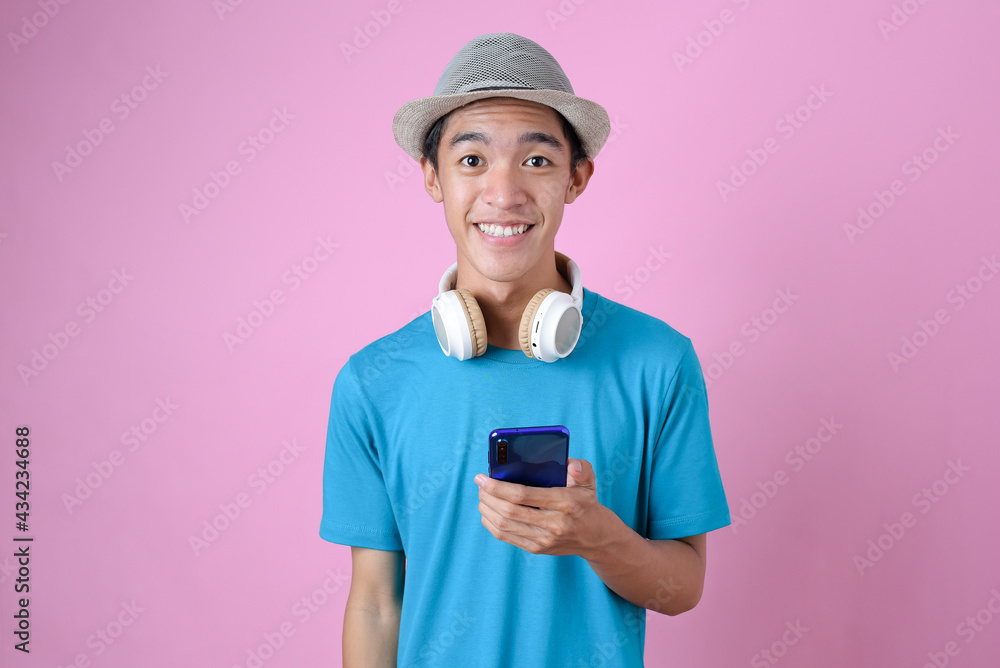 Portrait of happy young asian traveler holding a mobile smartphone with headphone Portrait of happy young asian traveler holding a mobile smartphone with headphone