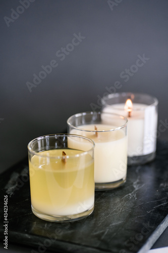 Three candles stand on the table on a gray background.
