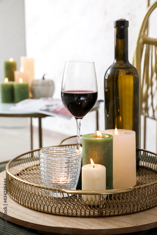Tray with burning candles and wine on table in room, closeup Tray with burning candles and wine on table in room, closeup