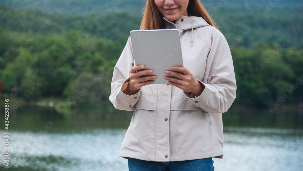 Closeup image of a woman holding and using digital tablet in the outdoors