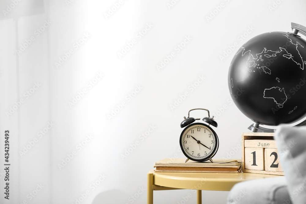 Table with alarm clock and globe near light wall Table with alarm clock and globe near light wall