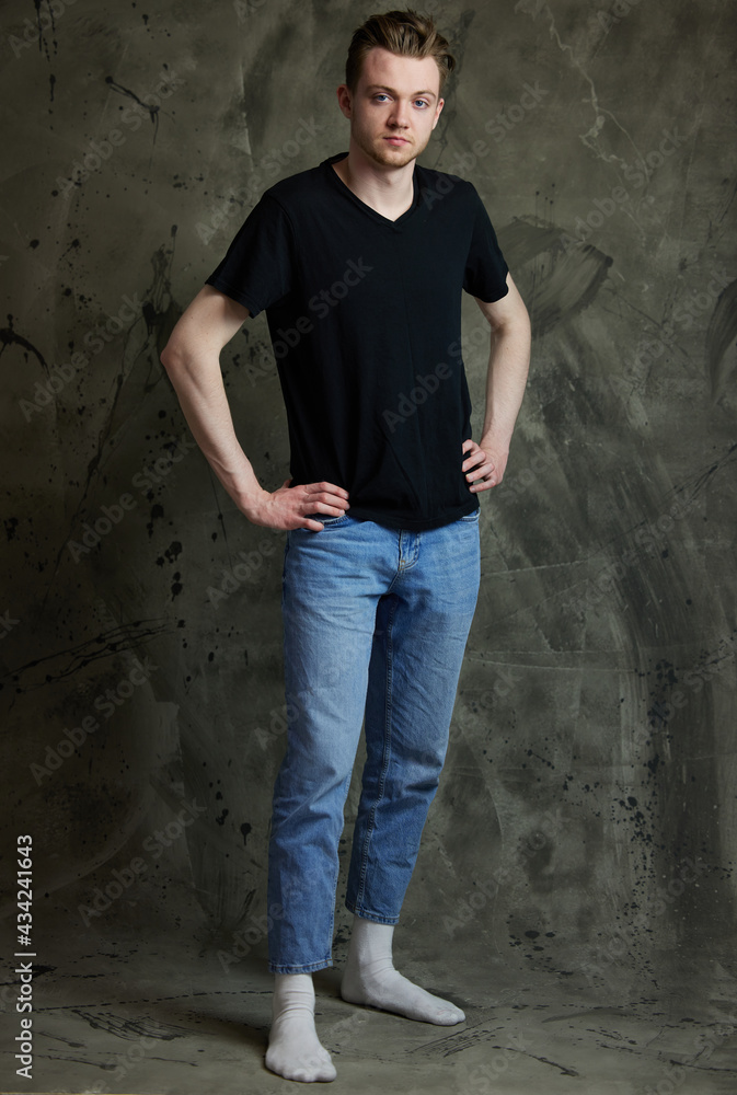 Horizontal portrait of a stylish caucasian guy in full growth on a gray background