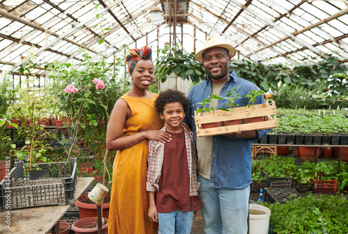 Portrait of African family of three smiling at camera and stnading in the greenhouse photo