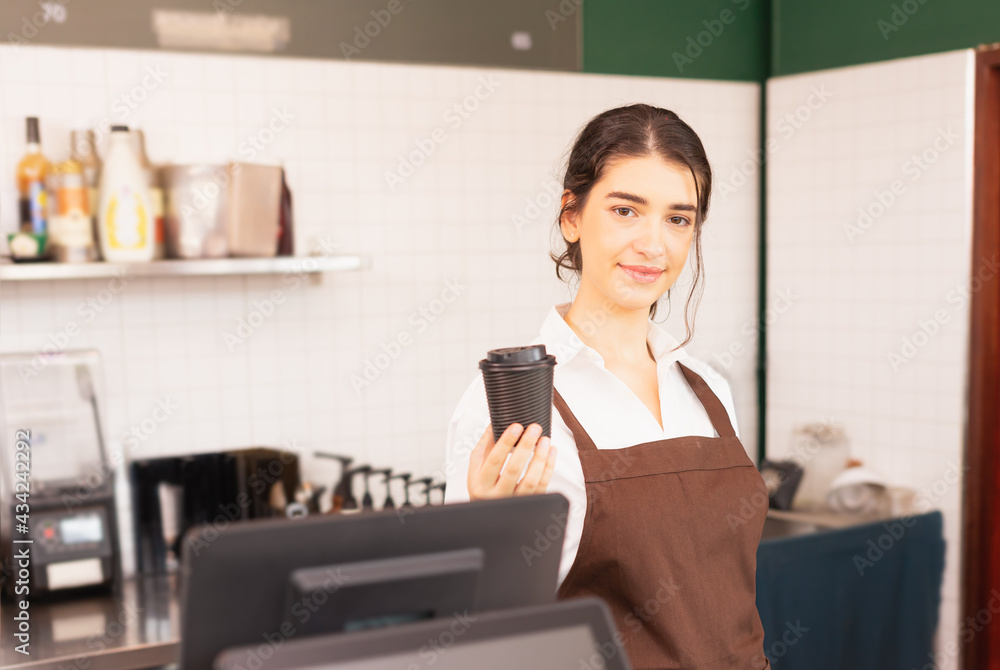 Beautiful caucasian barista woman show takeaway coffee cup in one hand at coffee bar Beautiful caucasian barista woman show takeaway coffee cup in one hand at coffee bar