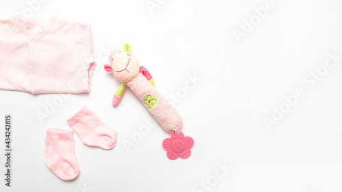 Baby clothes concept. Pink bodysuit for baby girl with socks and rattle toy. White Background. Copy space. Top view