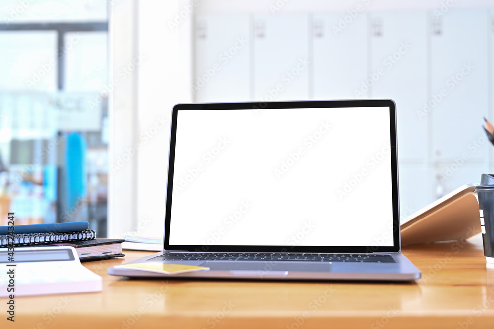 Close up view laptop with blank screen and calculator on wooden table. Close up view laptop with blank screen and calculator on wooden table.