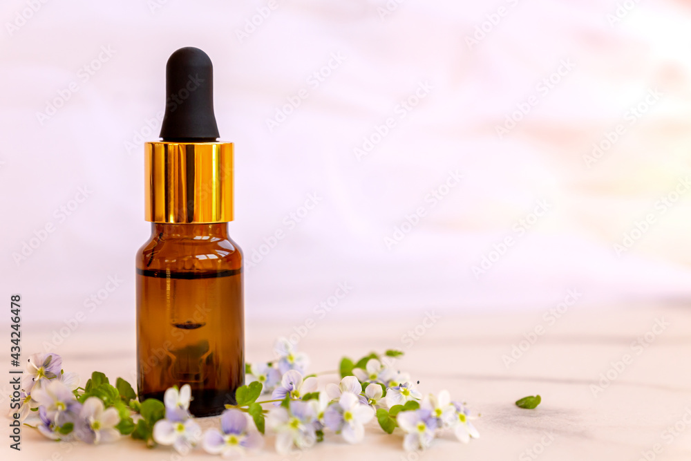 front view of Natural essential oil, serum glass drop bottle on a marble background wit wild flowers. Alternative medicine, aromatic herbal beauty skin care product. front view of Natural essential oil, serum glass drop bottle on a marble background wit wild flowers. Alternative medicine, aromatic herbal beauty skin care product.