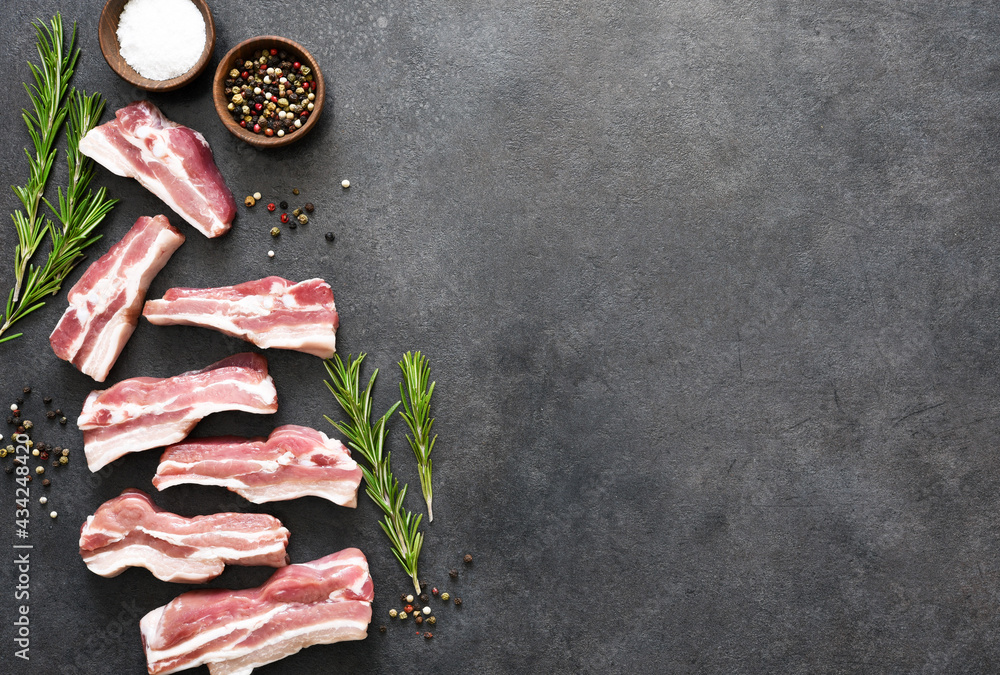 Raw pork rib with rosemary and an ax on a black stone background. View from above. Raw pork rib with rosemary and an ax on a black stone background. View from above.