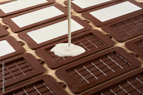 melted white chocolate with hazelnuts poured into a mold on a wooden table.