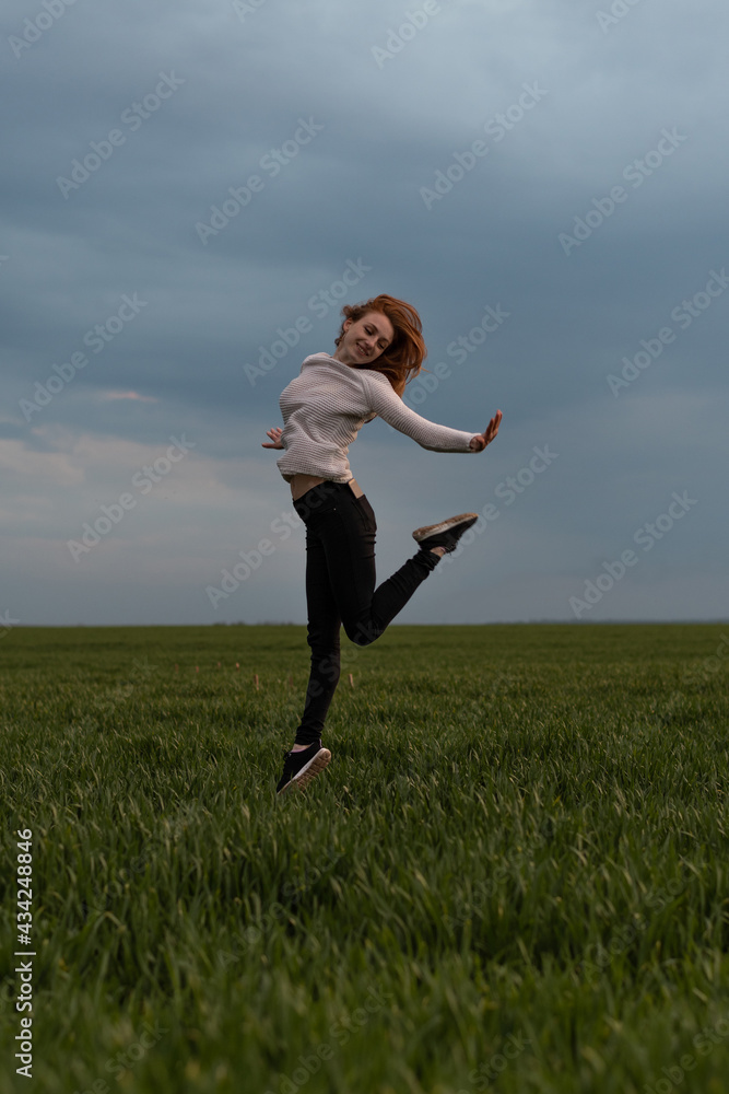Portrait of cheerful positive girl jumping in the field against stormy sky Portrait of cheerful positive girl jumping in the field against stormy sky