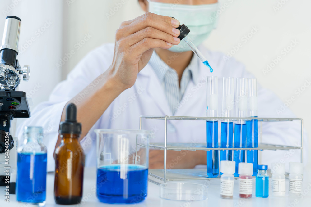 Scientist wear lab coat and protective wear are working with research or doing investigations with test tubes in experiment, Laboratory and development concept Scientist wear lab coat and protective wear are working with research or doing investigations with test tubes in experiment, Laboratory and development concept