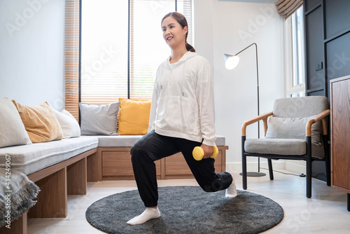 sporty woman in sportswear is sitting on carpet at home in the living room exercising, healthy and lifestyle concept.