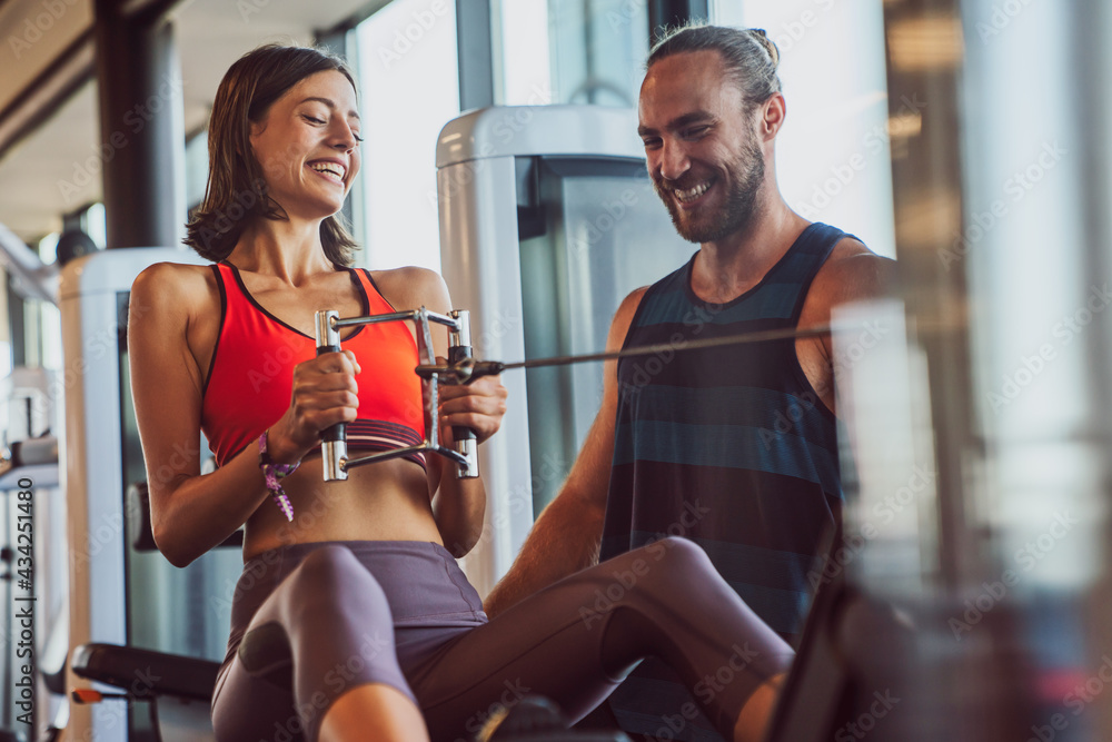 Personal trainer helping woman working out in gym Personal trainer helping woman working out in gym