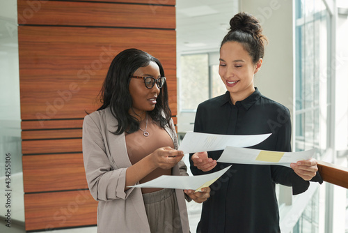 Two businesswomen working with documents and discussing contracts together while working at office
