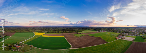 Beautiful aerial landscape of a rural countryside in panoramic view at the evening with a sunrise between some clouds.