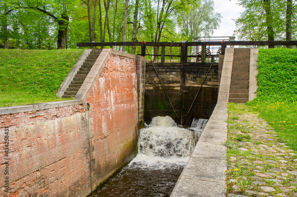 Old navigable river sluice. 20th century architecture with wooden mechanics. Augustow Canal, Belarus, 18 May 2021