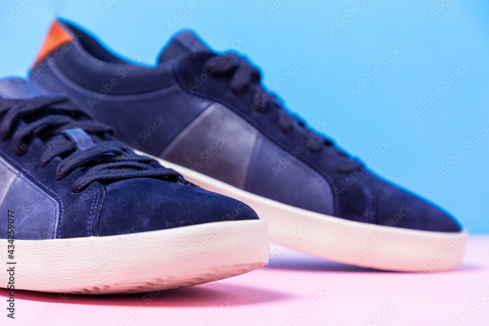 Man's new sneakers toes made of blue leather laid out on a pink-blue background. Close up