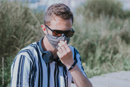 man with medical mask and headphones on the street, concept of leisure in the new normal photo