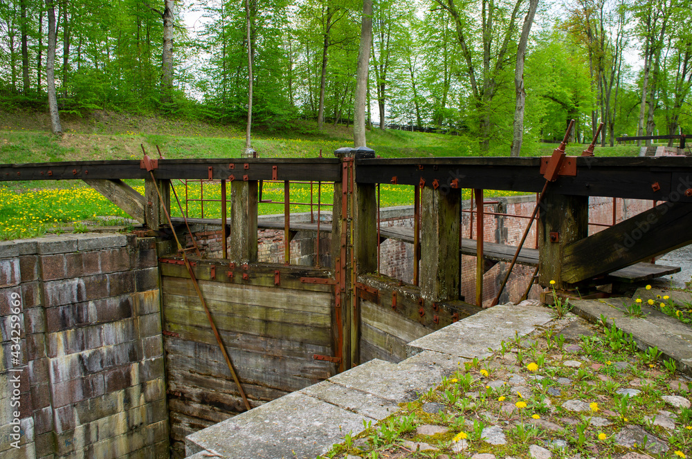 Old navigable river sluice. 20th century architecture with wooden mechanics. Augustow Canal, Belarus, 18 May 2021 Old navigable river sluice. 20th century architecture with wooden mechanics. Augustow Canal, Belarus, 18 May 2021
