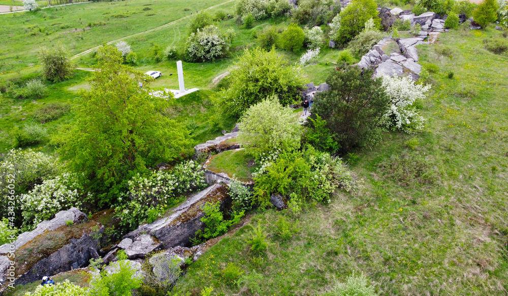 A view from a height on a stone rock ruins in a green field. Remains of an old fort of World War II