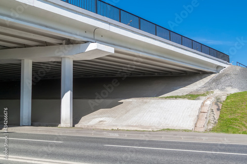 empty paved road and overpass with green grass on slope