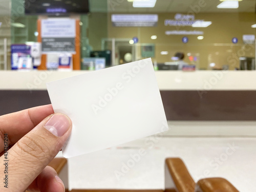 Obraz na płótnie Young man hand holding blank cue card with blurred cashier counter background, Y